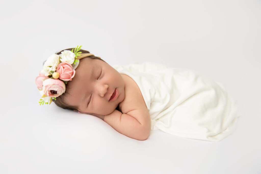 Newborn sleeping peacefully on a soft, neutral-toned blanket in a Wells, Maine photography studio.